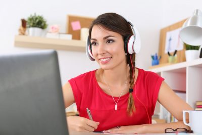 46188854 - beautiful smiling female student using online education service. young woman looking in laptop display watching training course and listening it with headphones. modern study technology concept